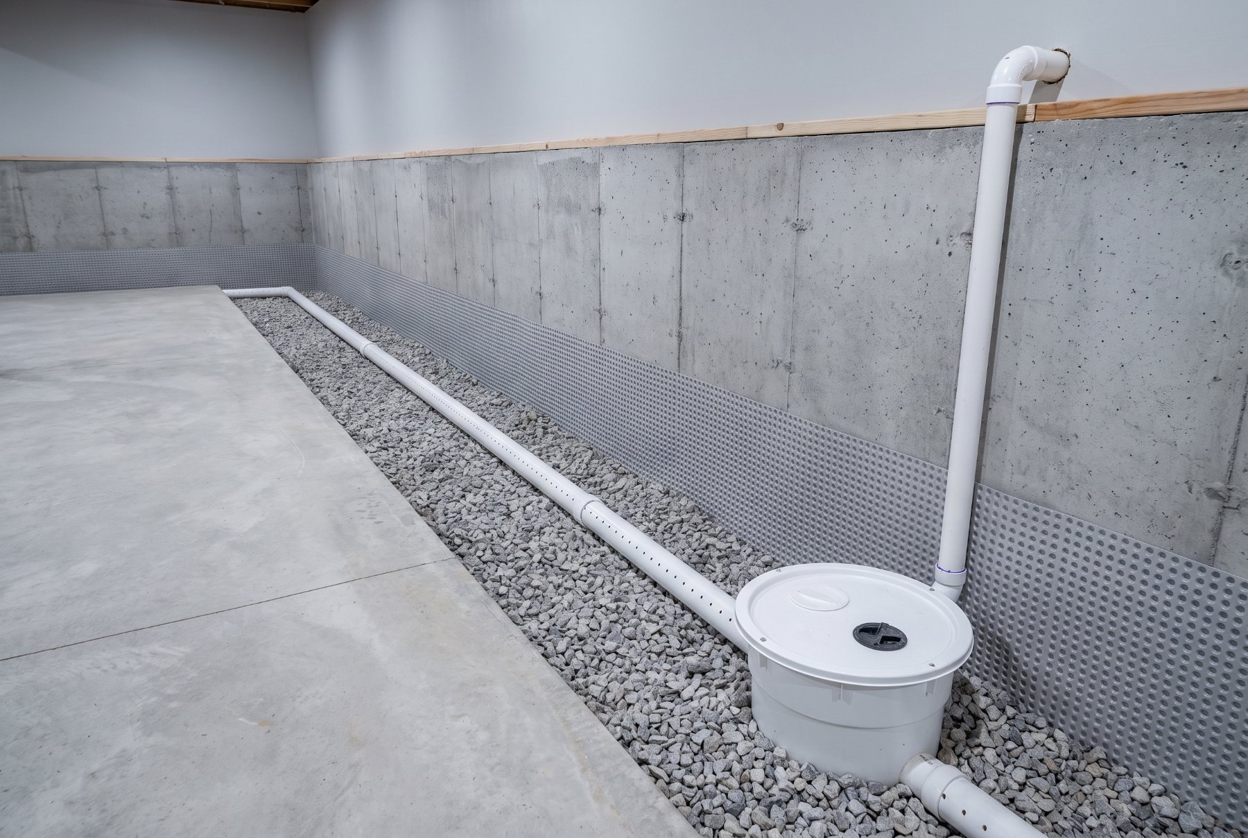 Completed interior drain tile system with washed gravel, a sealed sump basin and a clean discharge line in a Michigan basement